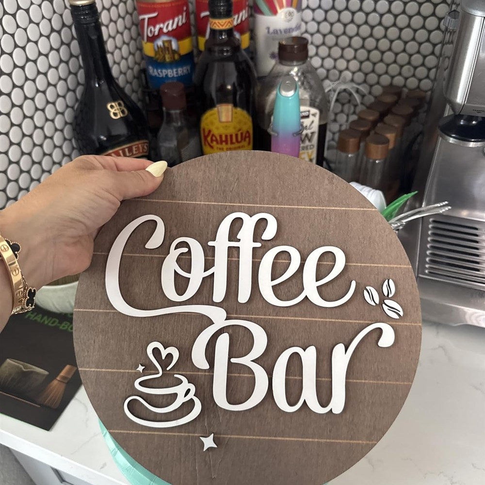 Round Coffee Bar wood sign held in front of a home espresso bar