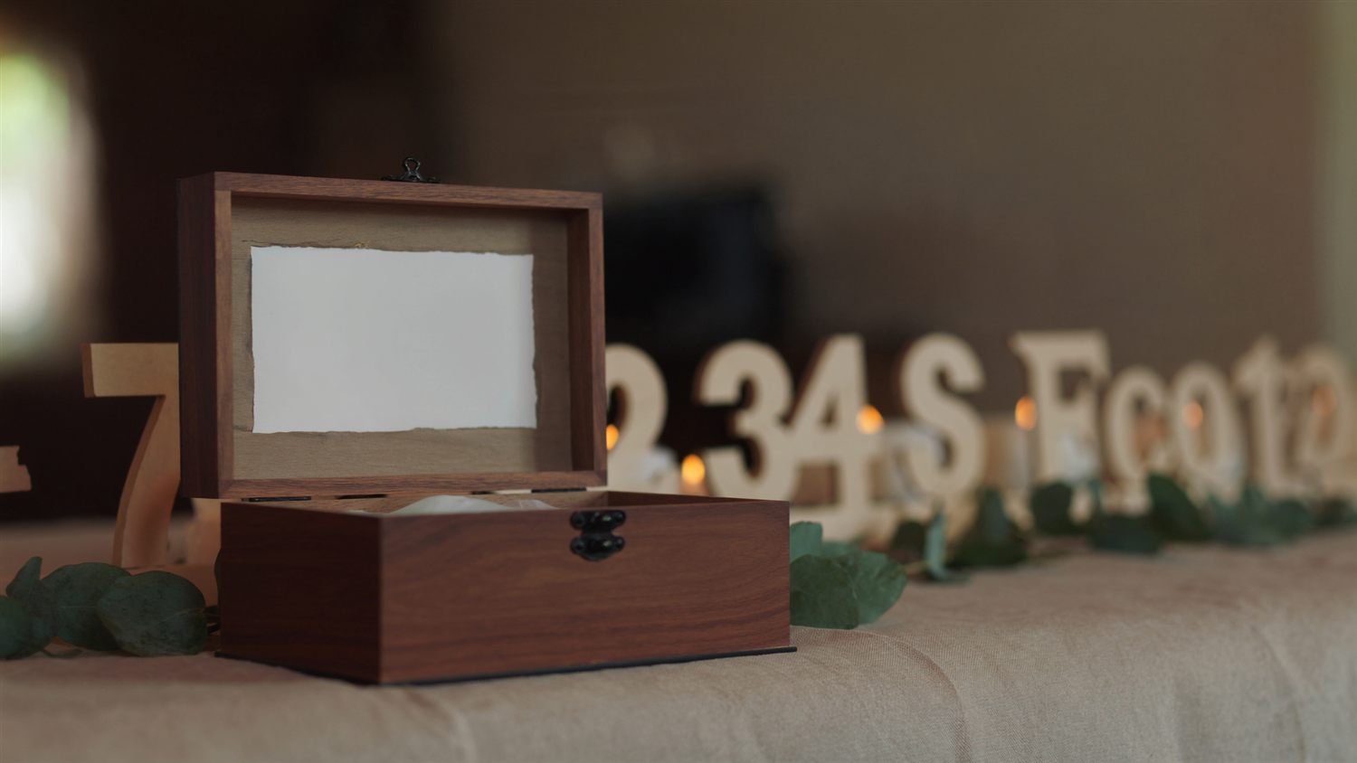 A wooden keepsake box and table numbers styled on a celebration table